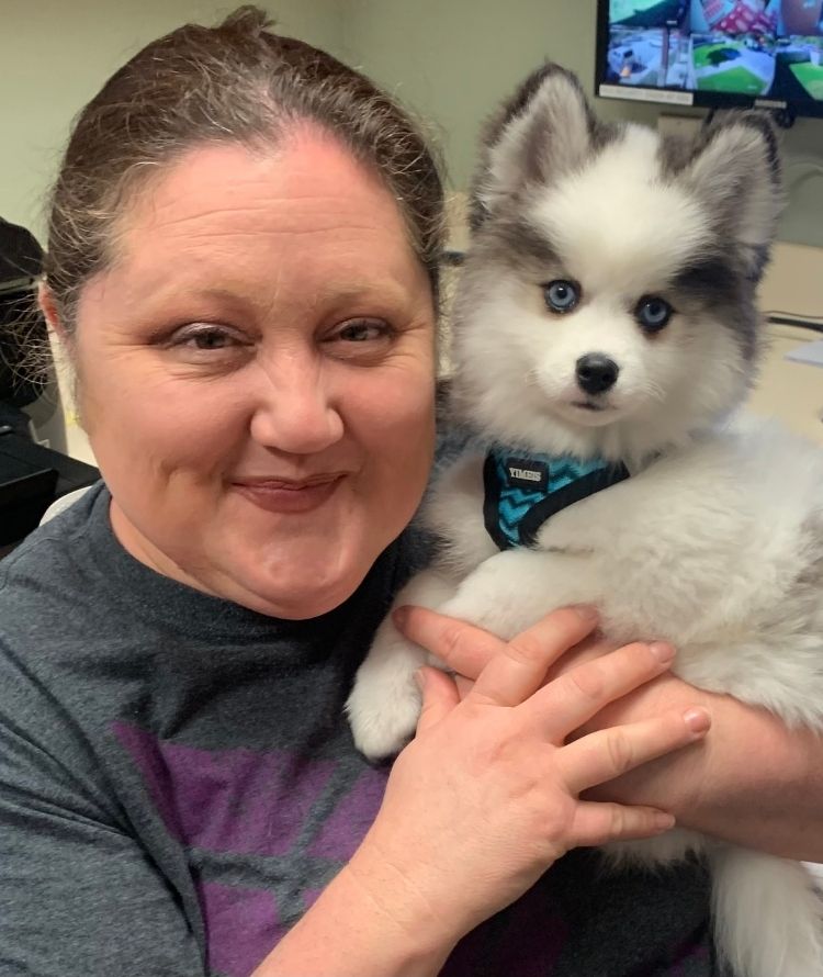 A vet gently holds a small white and gray dog in her arms