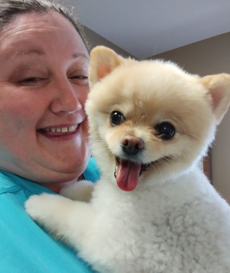 A woman gently holds a small white dog