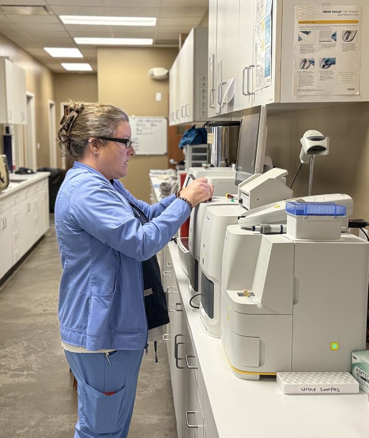 A woman wearing a lab coat is engaged in operating a machine